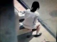 A disgusting bitch uses a bus station bench to urinate.